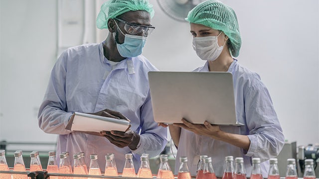 Factory worker in protective gear operating machinery in a food processing plant