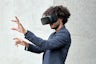 A man wearing virtual reality goggles interacts with a program.