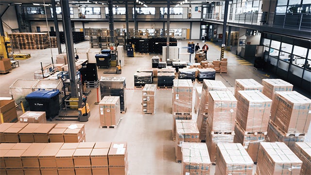 A modern distribution centre with a large warehouse and a modern building in the background.