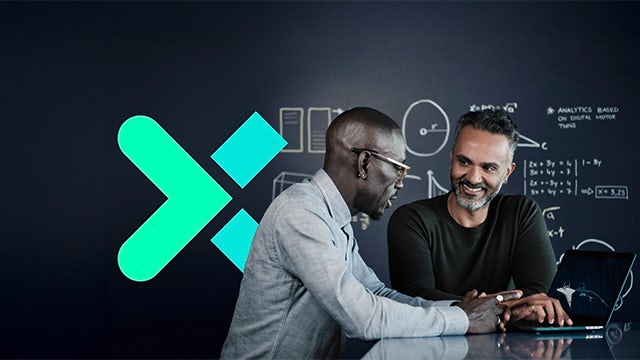 Two men collaborate in front of a chalkboard-style wall with diagrams with the Siemens Xcelerator 'X' logo in the background.