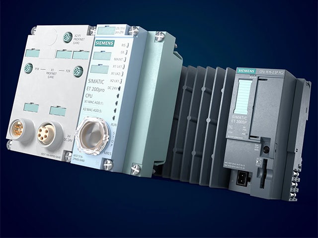 Industrial control panel with digital displays and buttons mounted on metal framework in a manufacturing setting