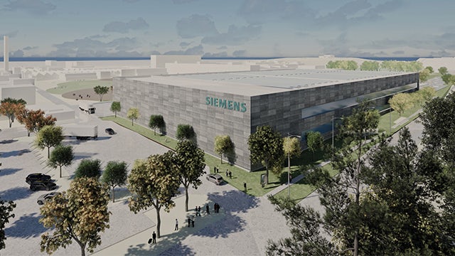 Modern Siemens industrial building in a landscaped campus setting, shown in a bright architectural rendering with trees, walking paths, and small groups of people around a large rectangular facility labeled “SIEMENS” under a partly cloudy sky.