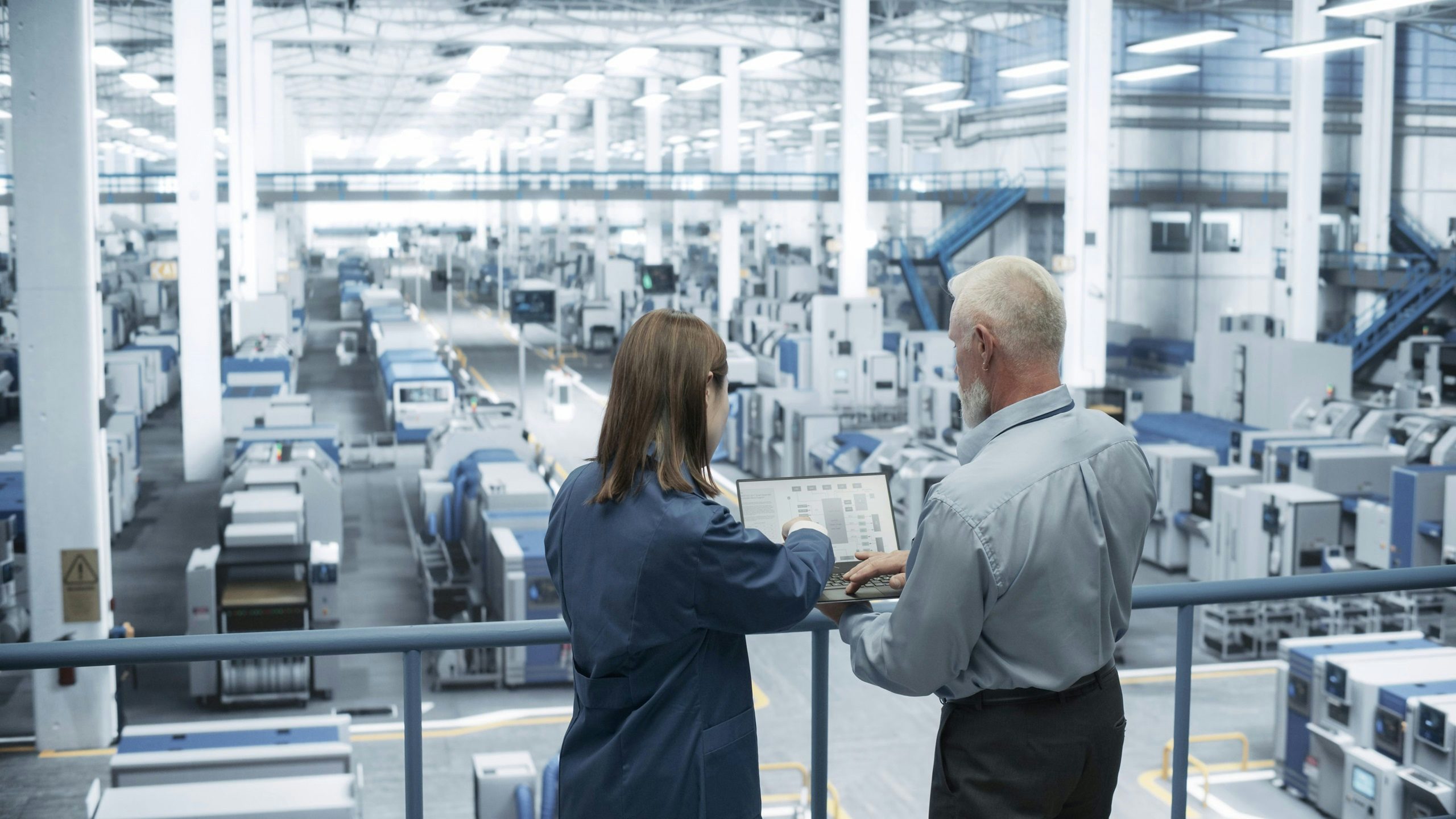 Two people using manufacturing systems simulation solutions in a manufacturing plant.