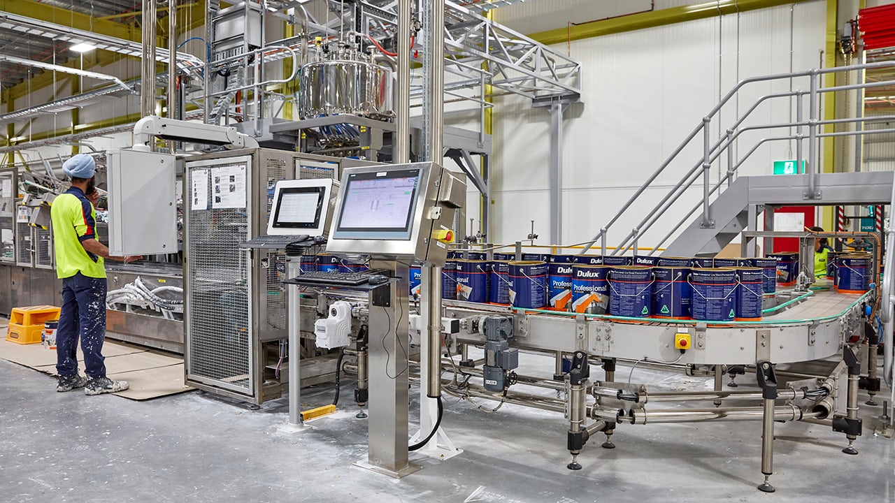 A factory worker operates a machine in a modern factory setting.
