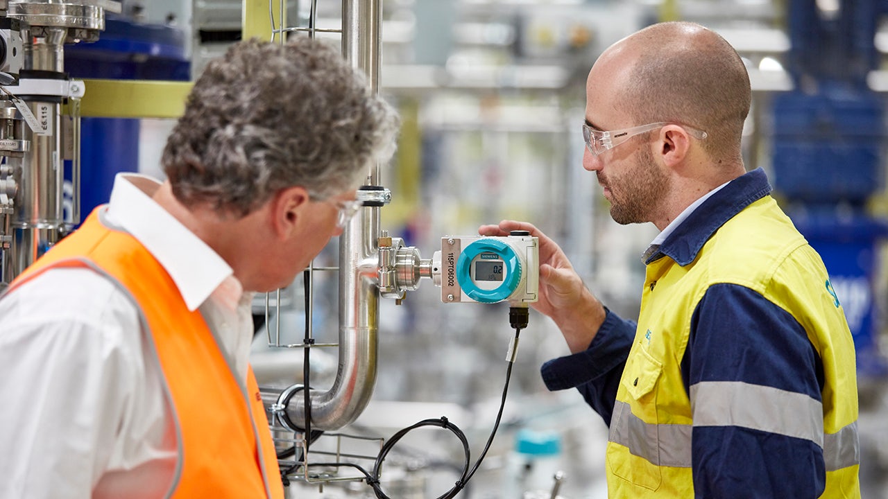 A group of workers are collaborating and assessing a project in a factory.