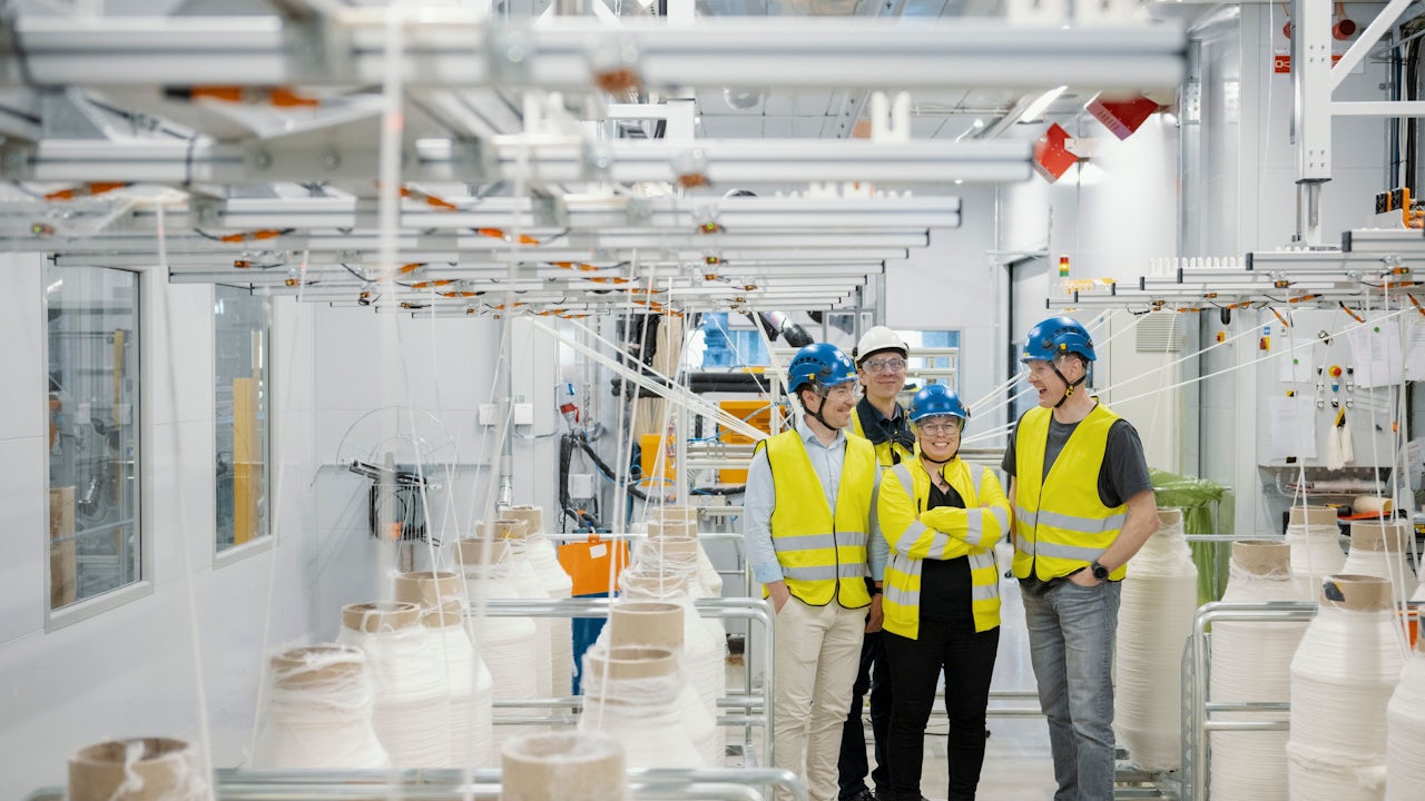 A group of people in a factory setting, possibly discussing or working on a project. 
