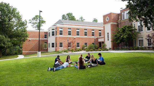 Students sitting outside on a campus lawn.