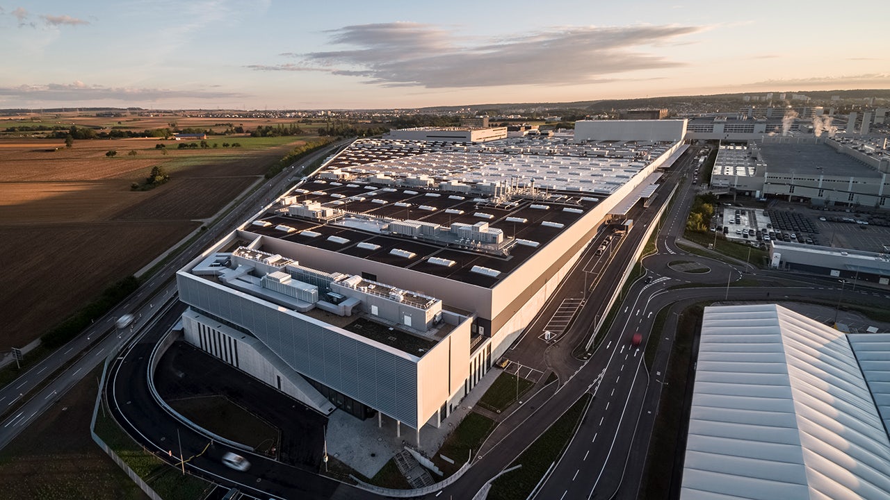 A factory with a Mercedes-Benz logo and a green field in the background.