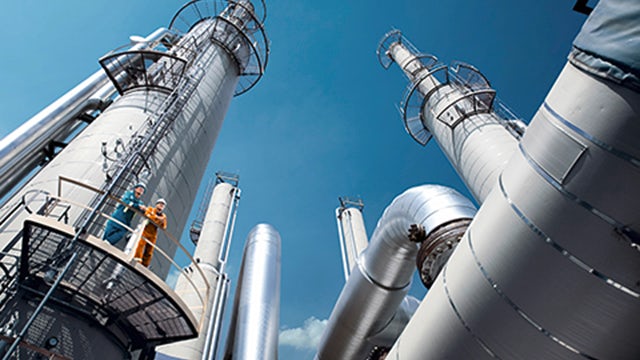 The image shows a large industrial facility with multiple tanks and pipelines, likely a tank farm or oil terminal.