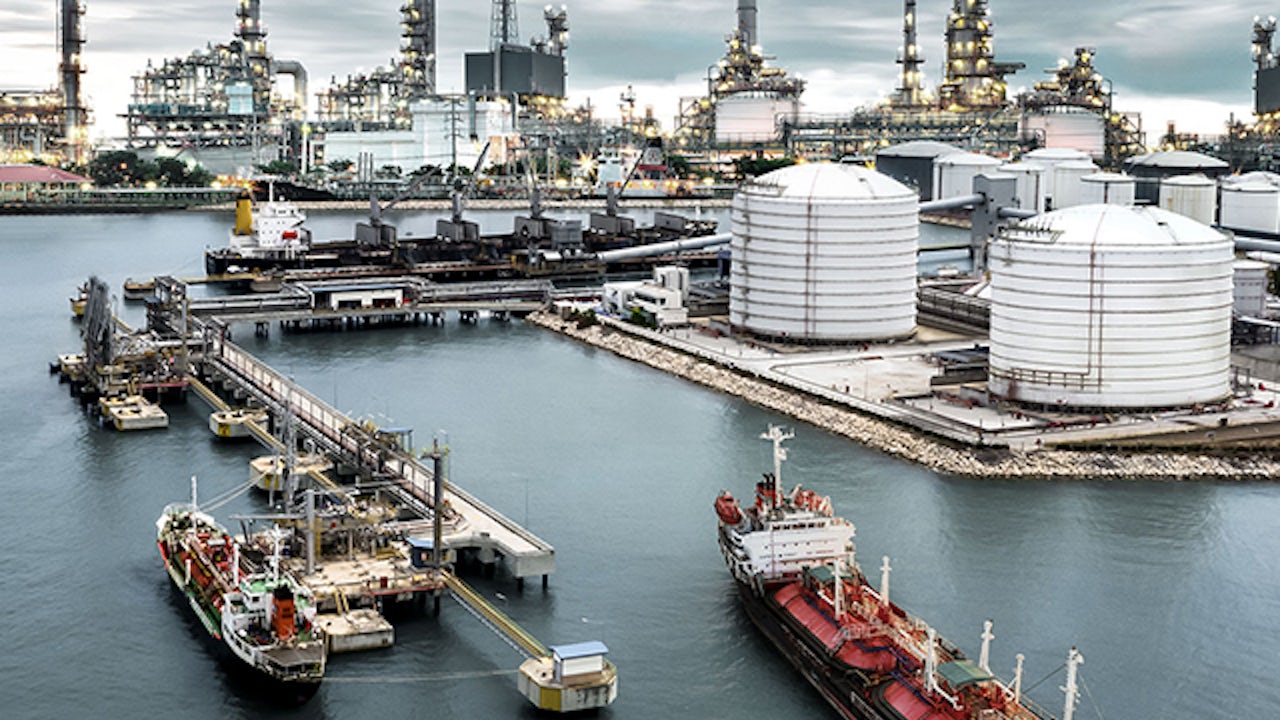 The image shows a port with oil and gas ships, tanks, and terminals.