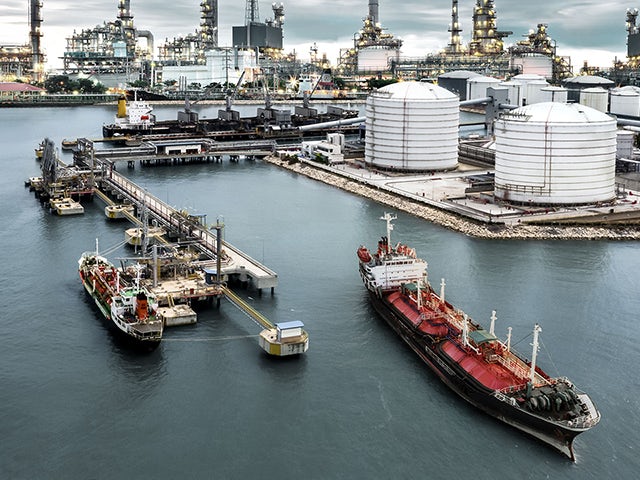 The image shows a port with oil and gas ships, tanks and terminals.