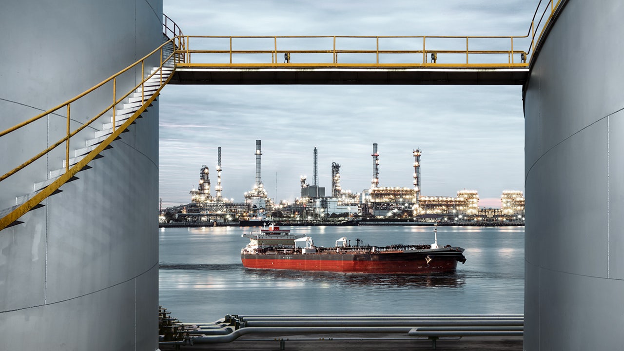 A ship is docked at a terminal, transferring oil or gas to a tank farm.