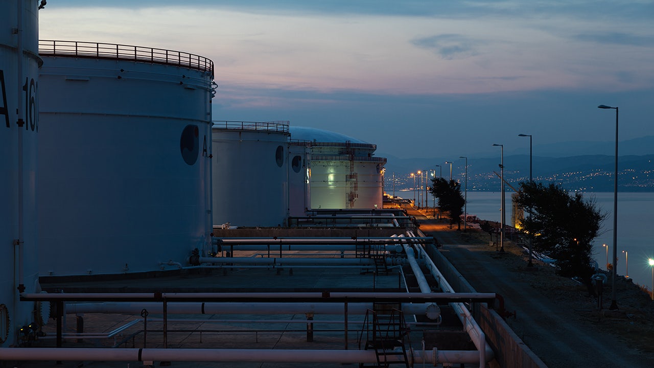 A sunset view of a tank farm with several large tanks and a terminal.