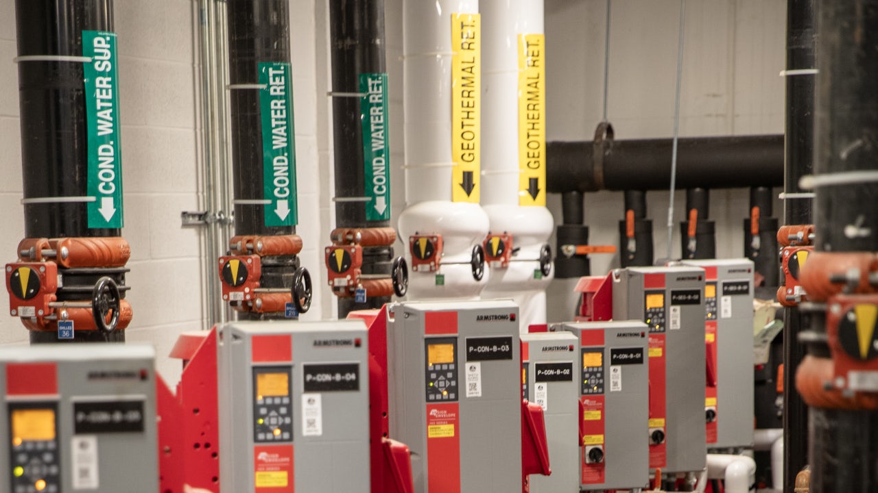 Mechanical room in the UTSC basement with labeled geothermal and chilled water pipes, valves, and control units supporting the building’s HVAC system. (uuid:9fb35ded-7f79-4f17-b18f-8c0e32b0b22b)