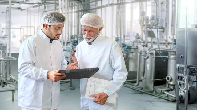 Two men, a Siemens engineer and a food plant worker, in a processing facility.